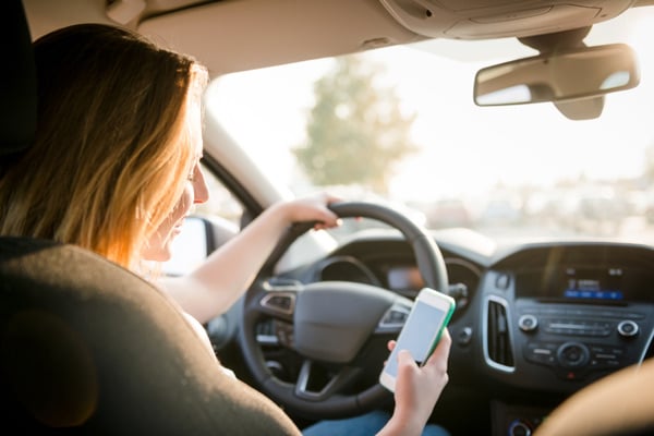 Woman driving, being distracted by cell phone