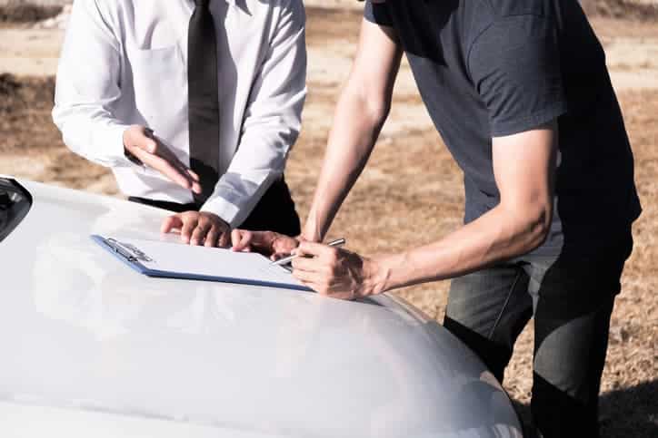 Two adults going over paperwork on car hood