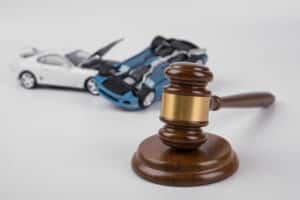 a gavel placed next to an image of two vehicles in a drunk driving accident. The blue car is flipped upside down and the white car is smashed into the blue one.