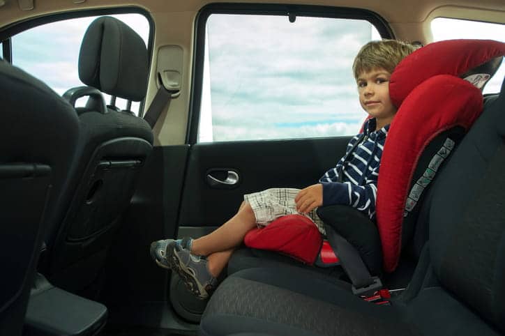 A child in a booster seat inside a car.