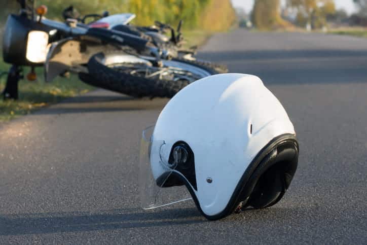 A white helmet in the road after a motorcycle accident. The bike is on it's side in the background.