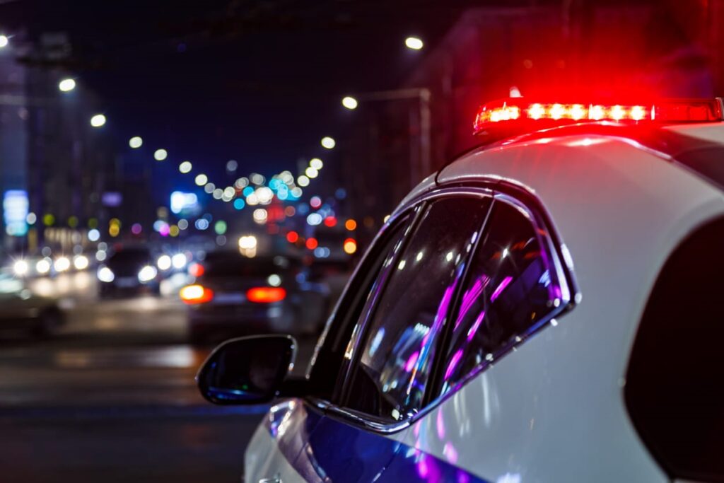 Closeup of a cop car with its lights on as it heads to a car accident.