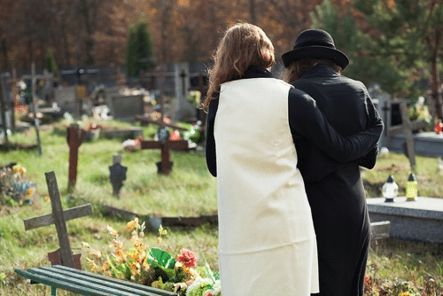 Two women standing in front of the grave of a loved one who died in a wrongful death situation