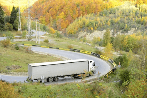 A semi truck driving on a very curvey road