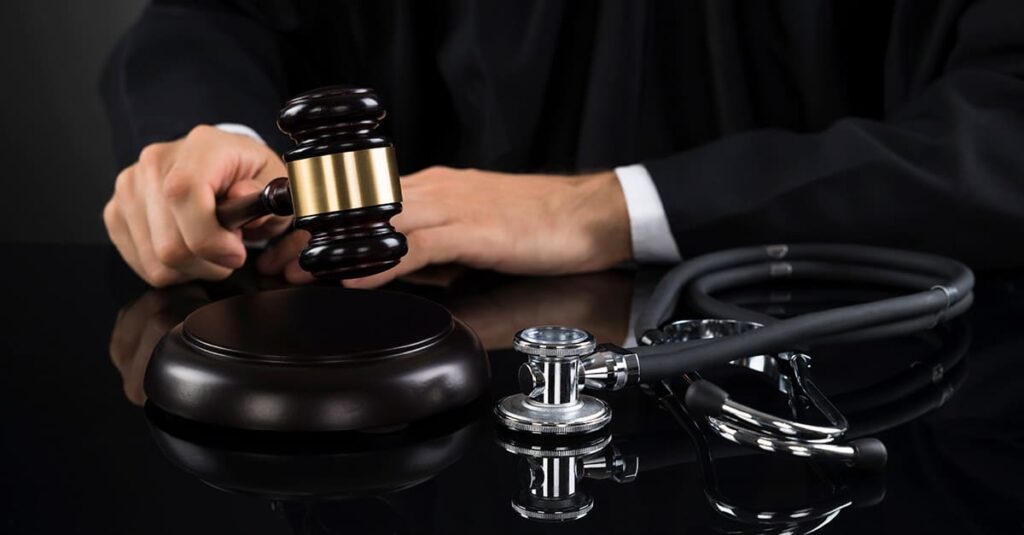 A judge holds a gavel with a stethoscope on the table representing medical malpractice law