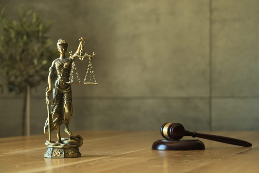 A Lady Justice statue next to a gavel on a slip-and-fall accident lawyer's desk.