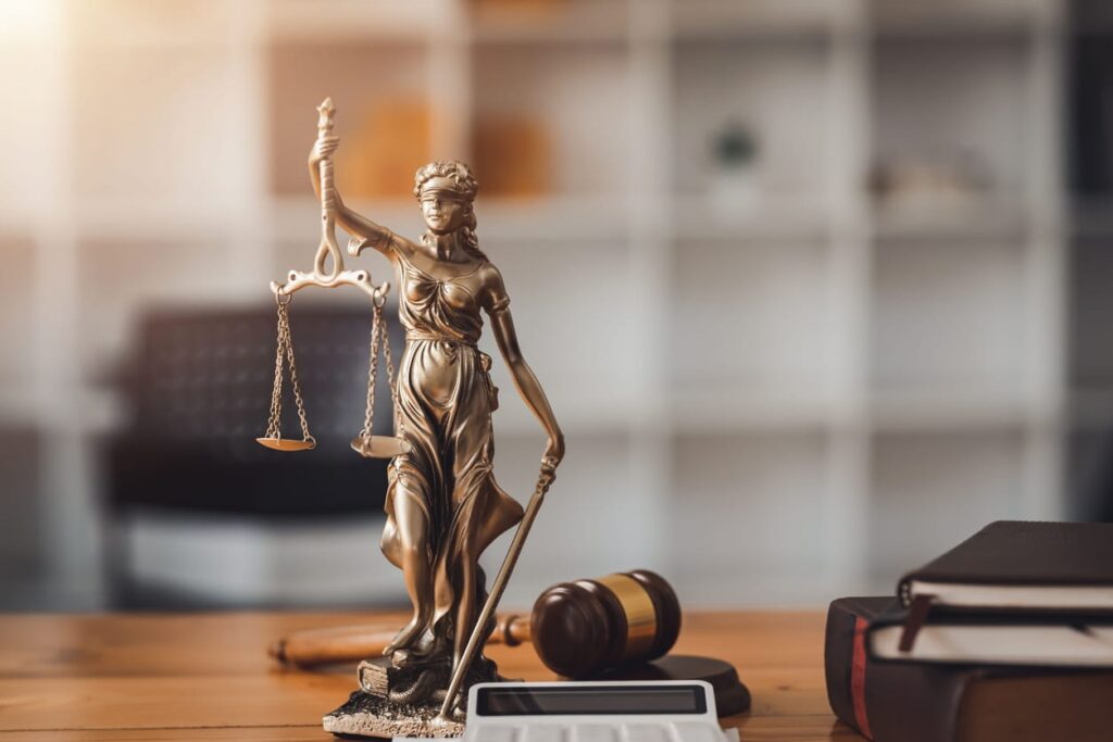 A Lady Justice statue next to a gavel and a stack of books on a medical malpractice lawyer's desk.