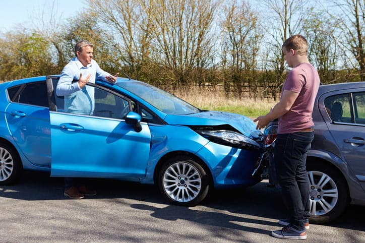 A rear end collision scene with two men out of their car looking at the damage