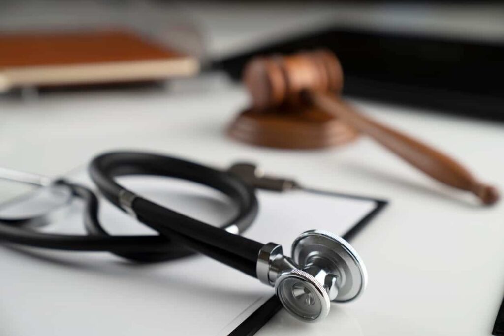 A stethoscope on a clipboard by a gavel.