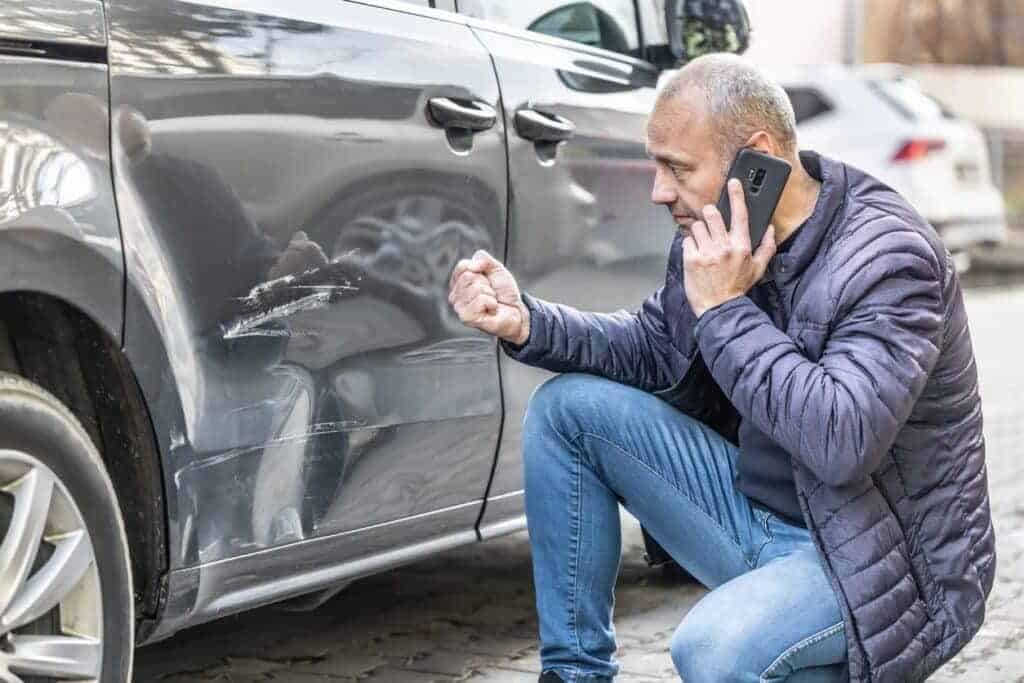 A man inspecting his car after an accident 