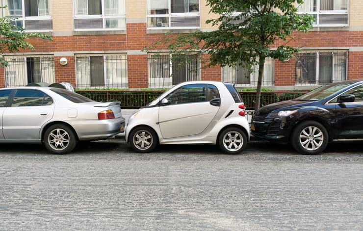 A Car Blocked Into A Parking Spot By Other Cars.