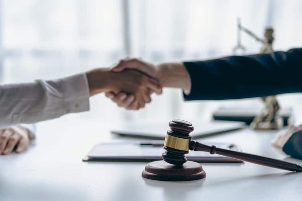 A car accident lawyer shaking hands with their client in Tampa. Between them is paperwork and a gavel.