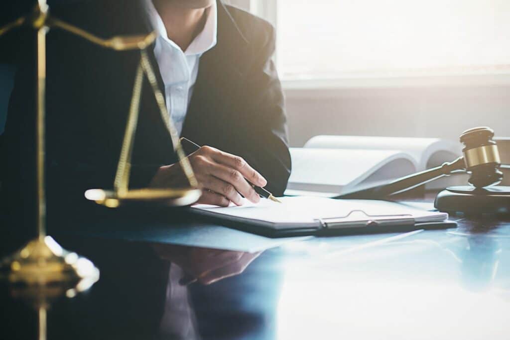 A Drunk Driving Accident Attorney Working On Paperwork At Their Desk In Tampa, Florida. Next To Them Is The Scales Of Justice And A Gavel.