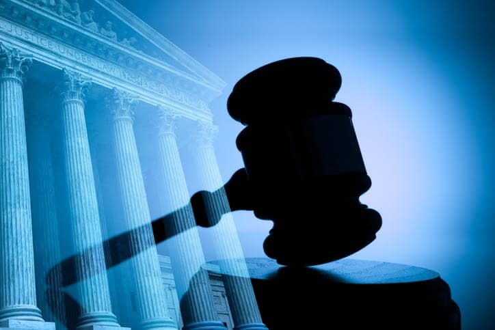 A graphic of a courthouse in blue with a silhouette of a gavel over it. 