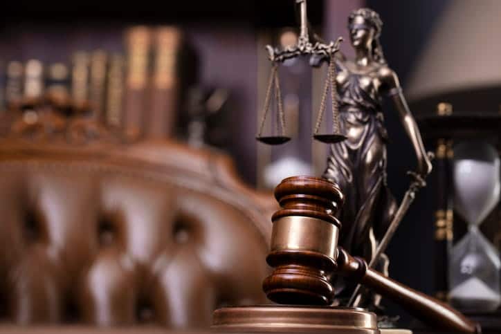 A gavel in front of a Lady Justice statue on a motorcycle accident lawyer's desk. 