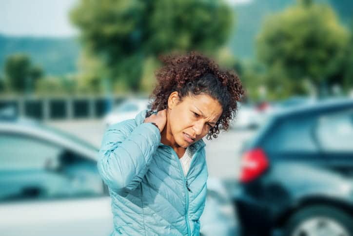 A woman holding her neck in pain after being in a car accident.