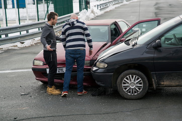 Two people inspect the damage after being involved in a car accident.