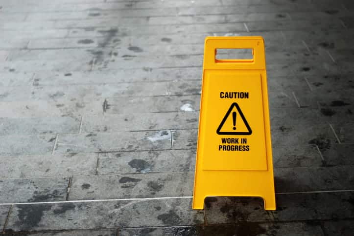 A yellow slip and fall prevention sign that reads: "Caution, work in progress"