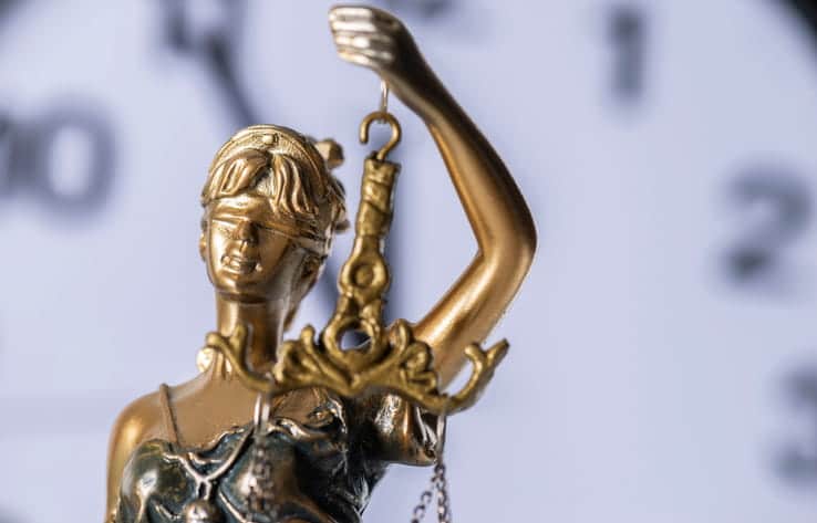 A Lady Justice statue standing in front of a clock.