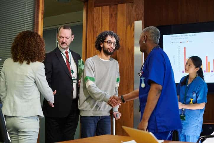 A man with a cane meeting with medical staff and attorneys

