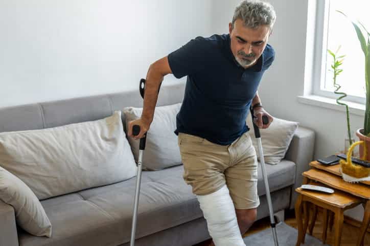 A man with a broken leg is trying to walk with crutches after a personal injury. 