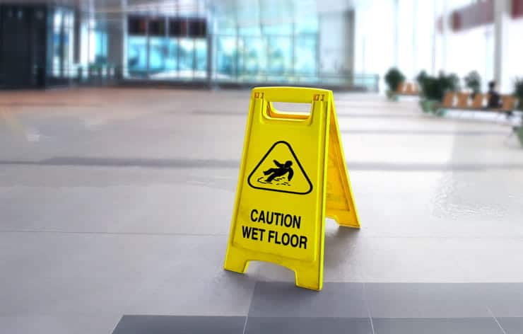 A yellow "caution wet floor" sign set out to prevent slip and fall accidents