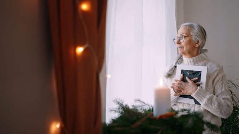 A Woman Who Lost A Loved One Holding A Picture Staring Out The Window