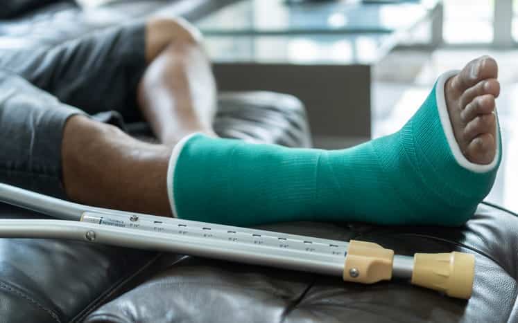 Focus is on man's broken leg that's wrapped in a green cast. 