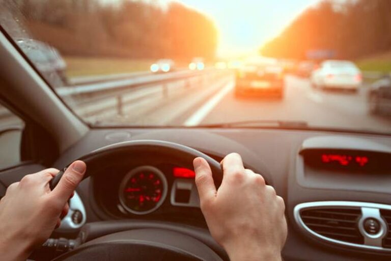 Focus Is On The Hands Of A Person Holding A Steering Wheel As They Drive A Car.