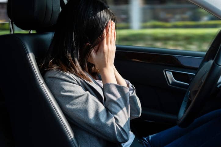 A Woman Sits Behind The Steering Wheel Of A Car As She Covers Her Face With Her Hands In Distress. , Picture
