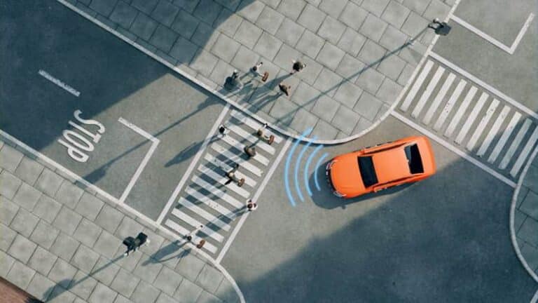 An Aerial Image Of A Self-Driving Car Using Sensors To See People Crossing A Crosswalk.