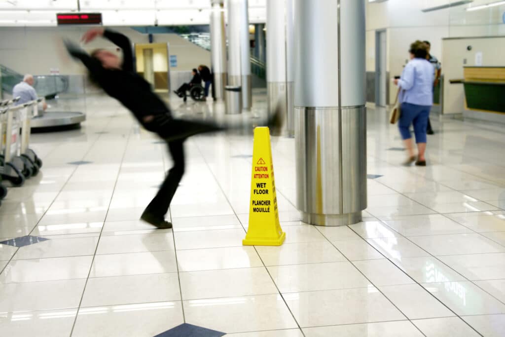 Slip And Fall Accident At An Airport Next To A Wet Floor Sign